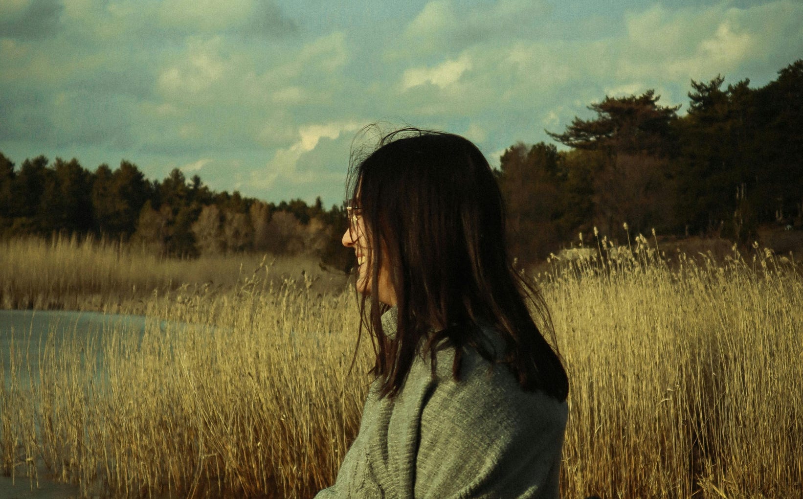 Young Woman Standing on a Lakeshore in Autumn 